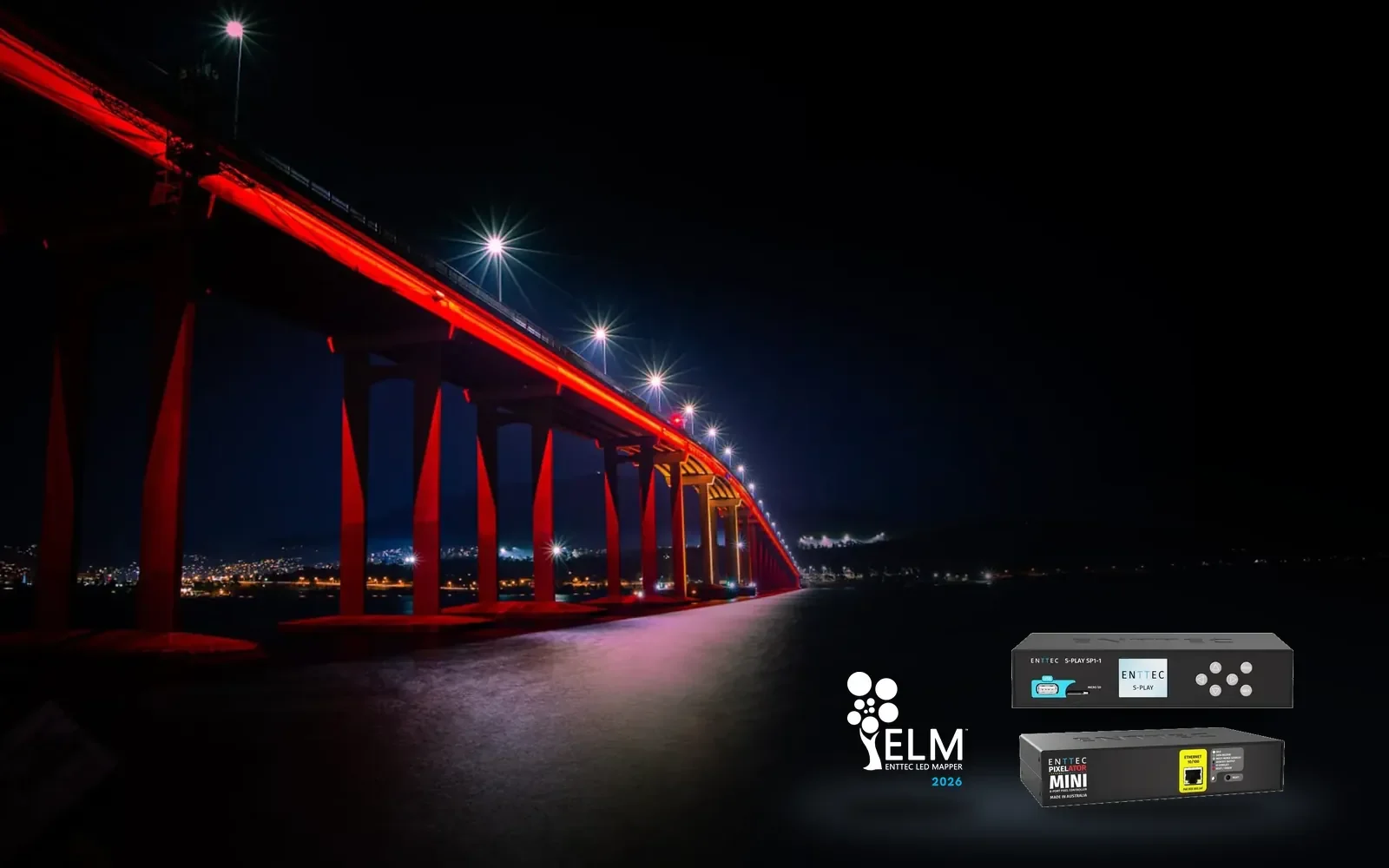 Tasman Bridge at night from the shoreline, its piers washed deep red and a pool of pale light on the water below