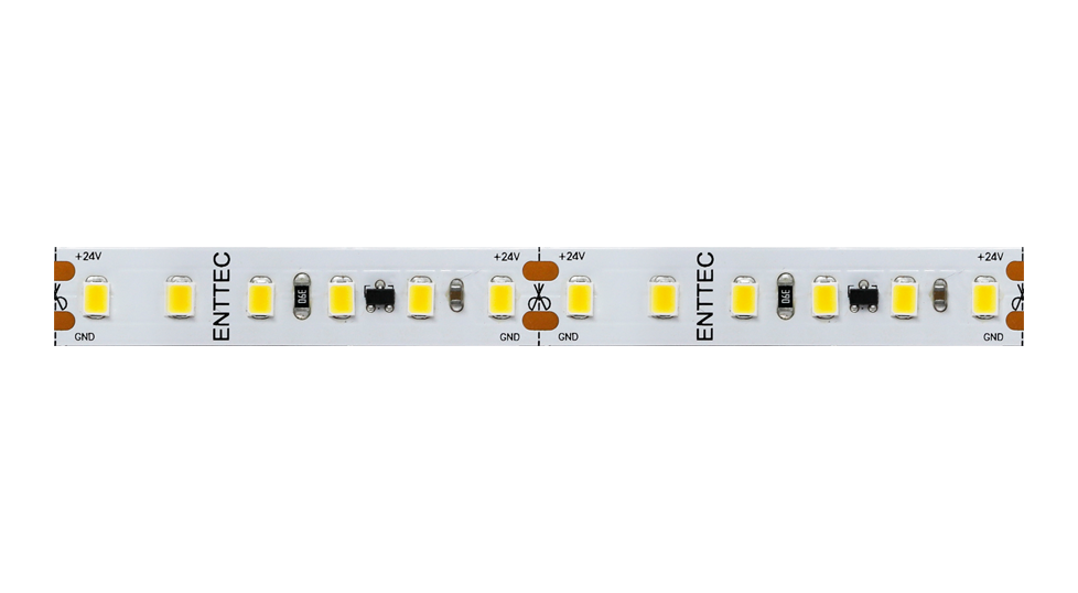 A length of the white LED strip on a plain background, densely packed white SMD emitters and resistors either side of a scissor cut mark, ENTTEC printed on the board and +24V and GND solder pads along both edges.