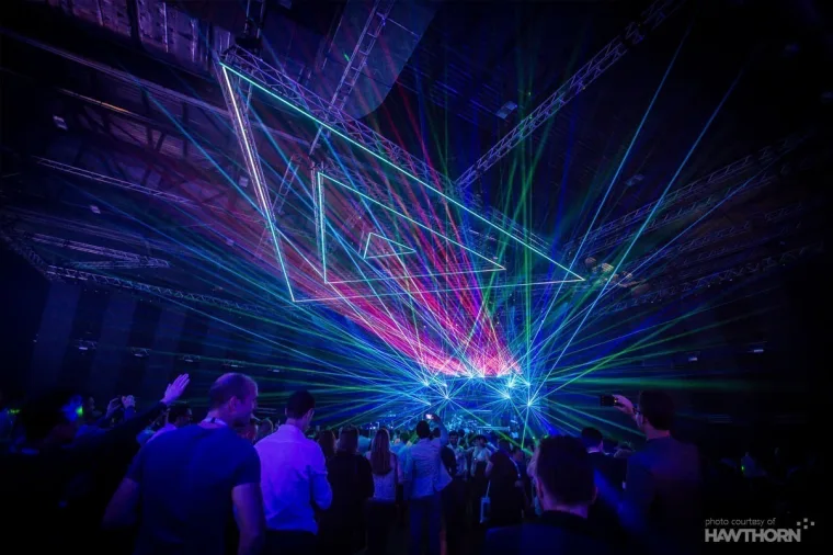 Lasers criss-crossing above the Neon Super Club crowd, with lit triangular frames in the roof structure
