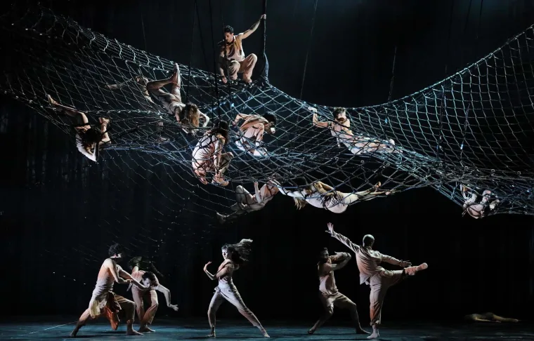 Dancers draped along a huge net slung across the stage, more of the company reaching up from below