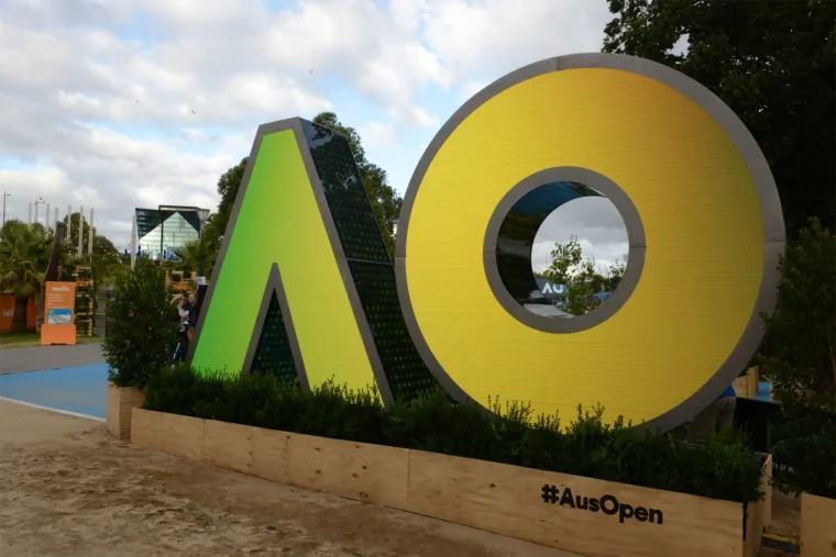Daytime view under cloud, the letters in flat yellow and green above a timber planter marked #AusOpen