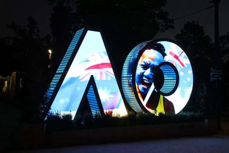 Australian flag artwork and a smiling player's face across the letters at night, dark trees behind
