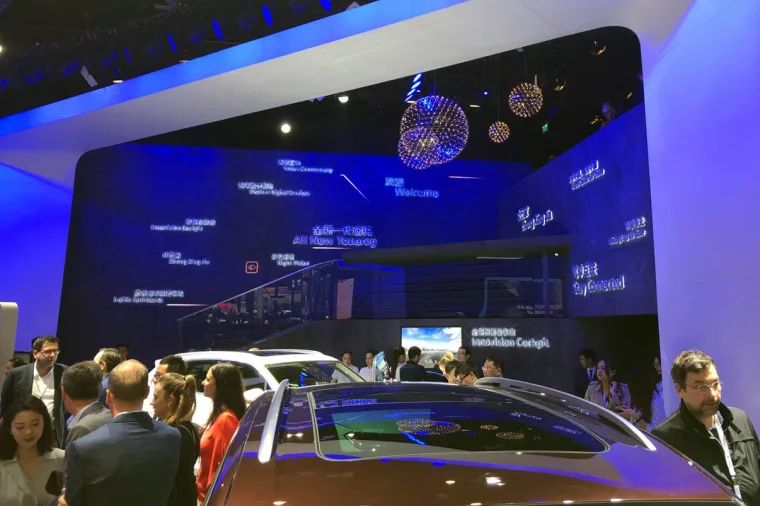 Visitors packed around a car roof while the blue wall and its mirror balls glow behind the Innovation Cockpit screen