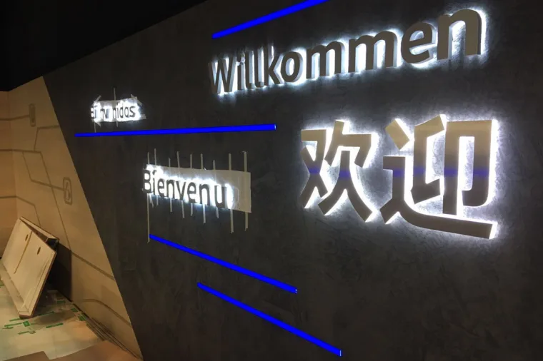 Close on the welcome wall, Willkommen, Bienvenue and the Chinese greeting picked out in light with blue pixel strips running between them