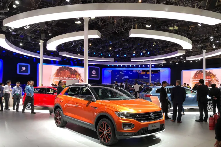 Wide view of the stand from the aisle, the full array of lit rings overhead and visitors circling the orange T-Roc