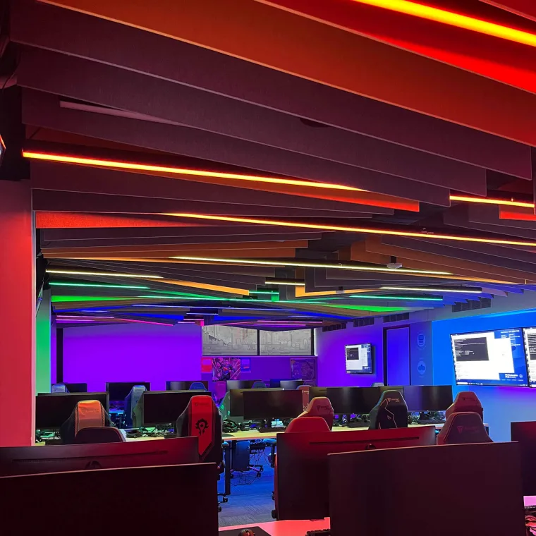 Ceiling battens in red, orange and yellow overhead, fading to green and blue further down the room with students at the desks