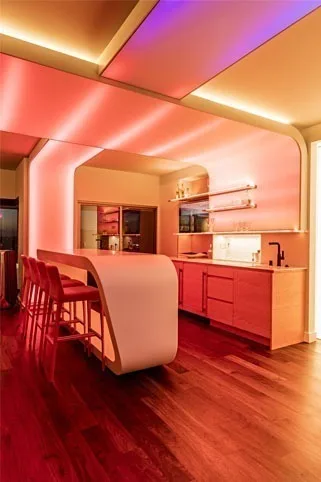 The same bar in warm coral and pink, light raking across the angled ceiling planes and the timber floor