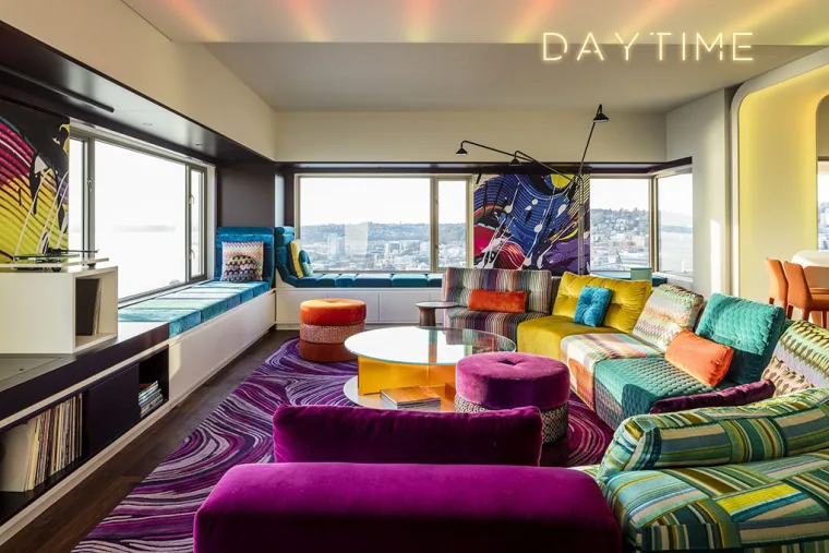 The lounge under neutral daytime lighting, the word Daytime set into the ceiling glow above the patterned sectional