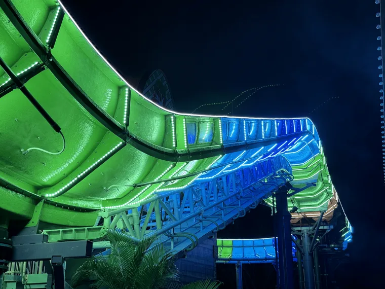 A green run flowing into a blue and cyan section, seen along its length with a walkway lit underneath