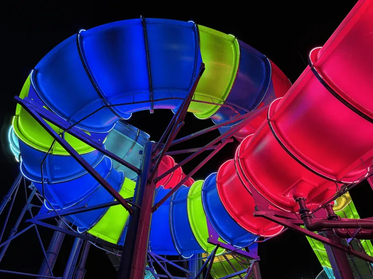 Blue coils of tubing overhead with green and magenta runs threading through, photographed from directly beneath
