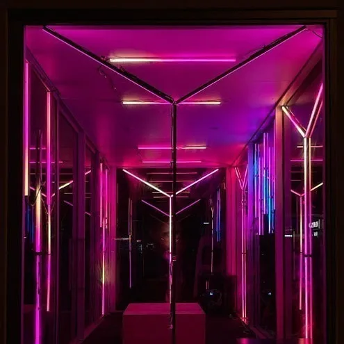 Inside the Boom Box in hot pink, V-shaped light bars running along both walls and the ceiling toward a bench at the far end
