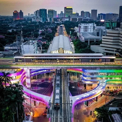 Dusk view along the MRT line, the lit skybridge in the foreground and the Jakarta skyline stacked up behind it