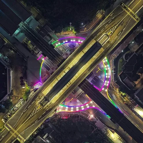 Straight down on the four lit walkways wrapping the elevated station, warm street lighting picking out the roads below