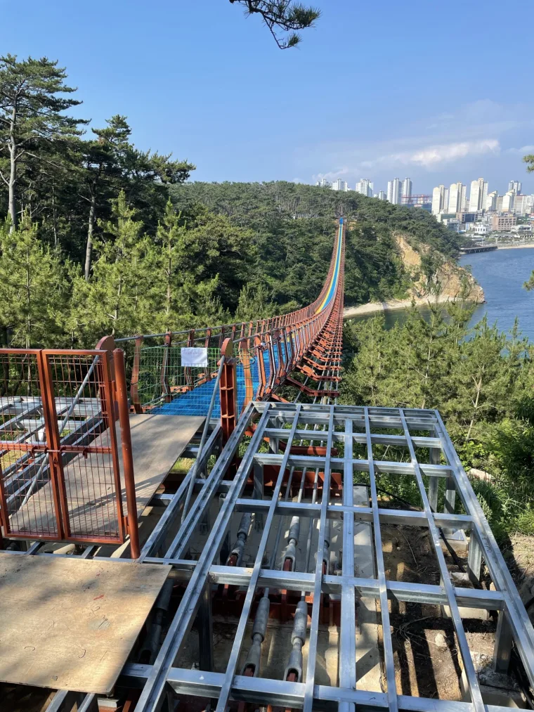 Steel deck framing at the landing during the build, the red span sweeping across the inlet toward the city skyline