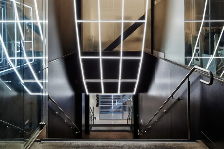 The same entrance from a half step to the right, the stainless handrail catching the light and the stair glowing blue below
