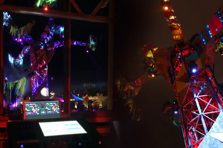 A lighting console and screen on a deck built into the sculpture, painted branches and fabric streamers rising around it