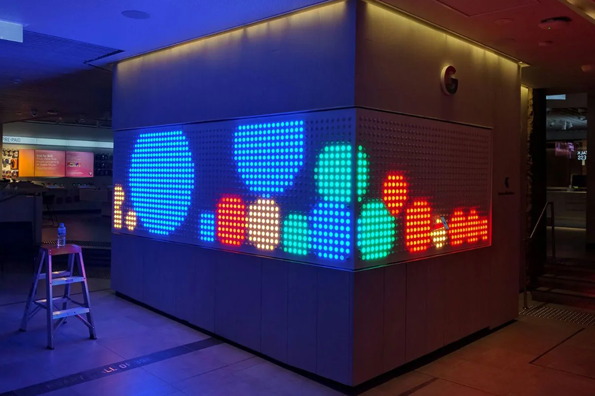 The wall under test in an empty store, blue, green and red blobs spread across the dots with a step ladder left in front