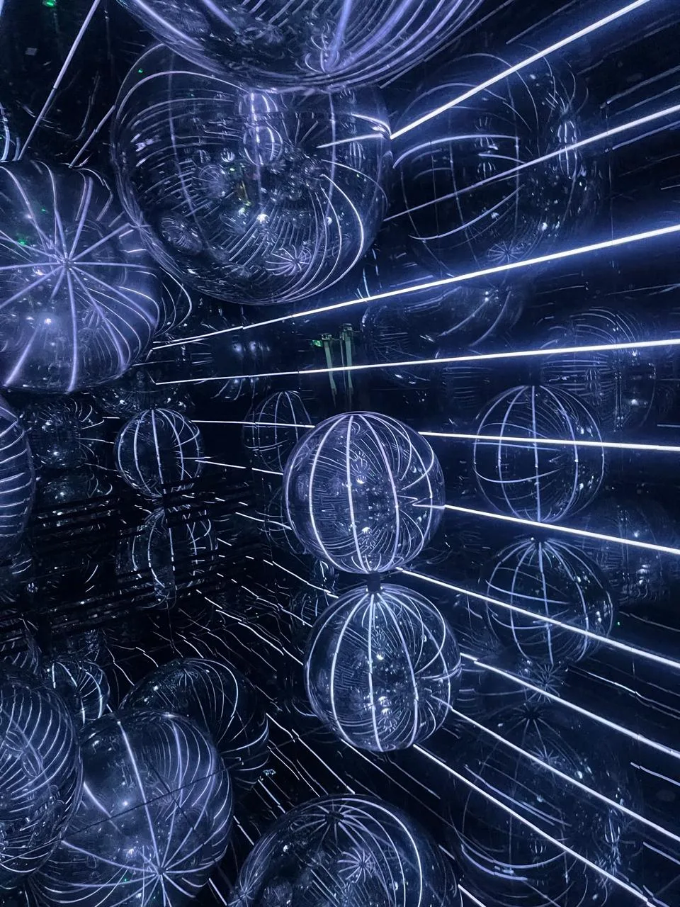 Dark mirrored room printed with wireframe globes, white neon lines shooting away in every direction