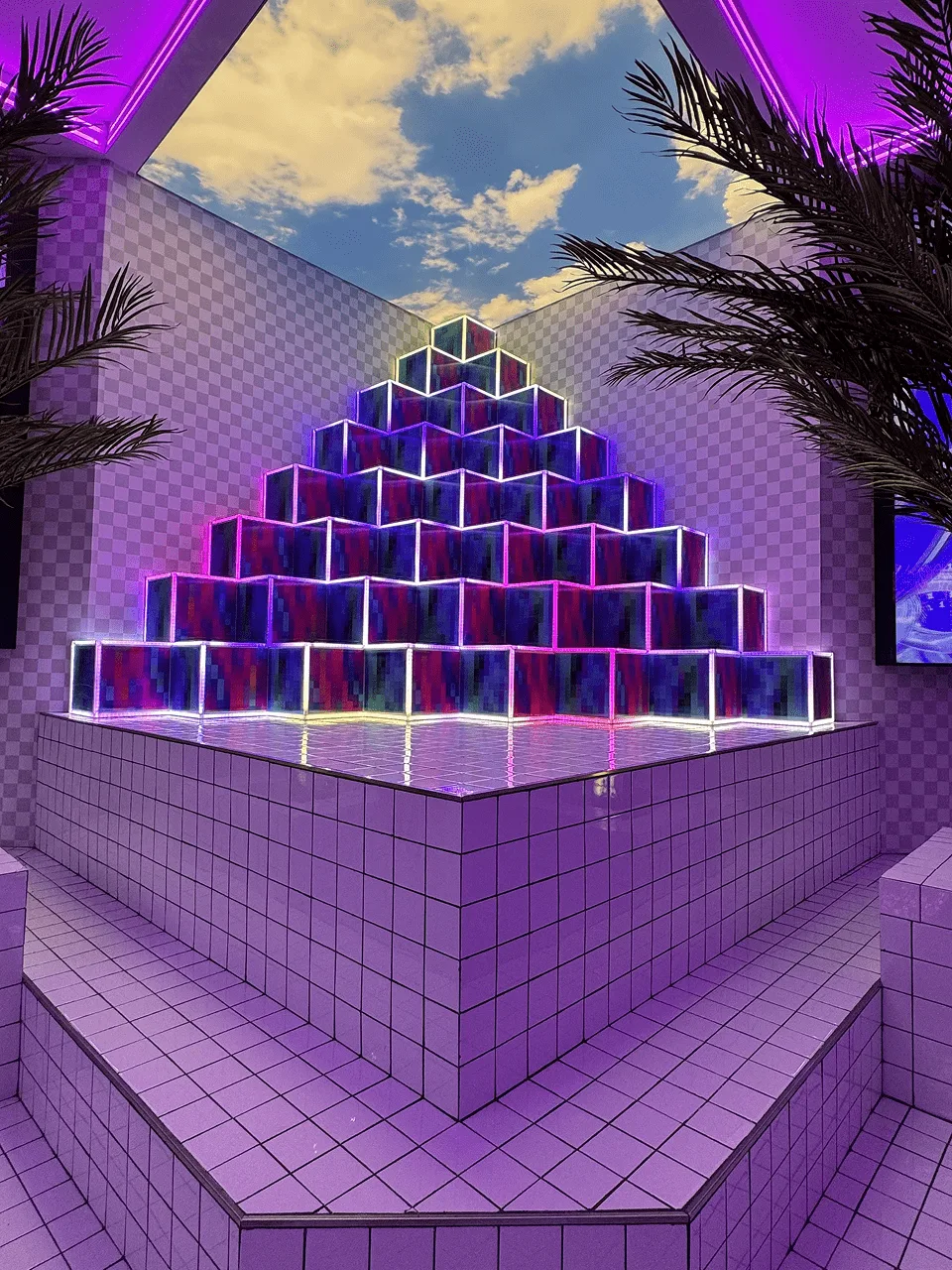 Purple tiled room with a stepped pyramid of light edged blocks, palm trees and a painted sky overhead