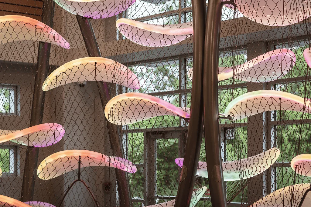 Close view of pink and green platforms strung between curved steel poles, safety netting stretched between them