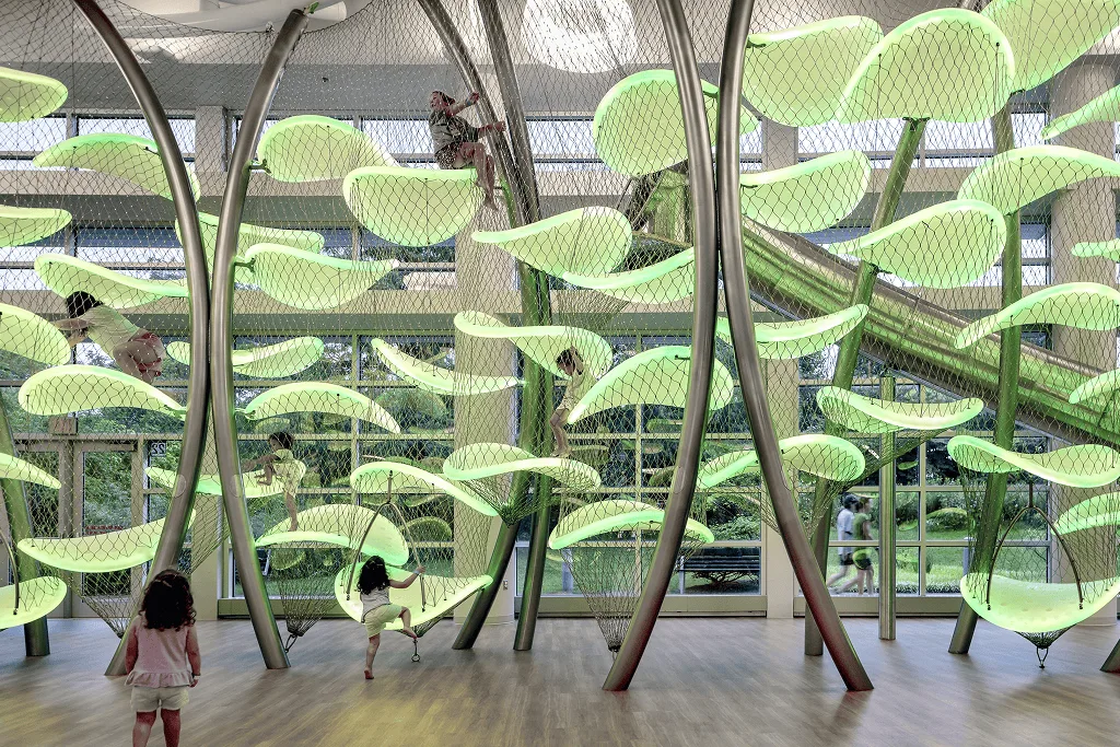 Two small children crossing the floor while another climbs above, the whole structure lit fresh green