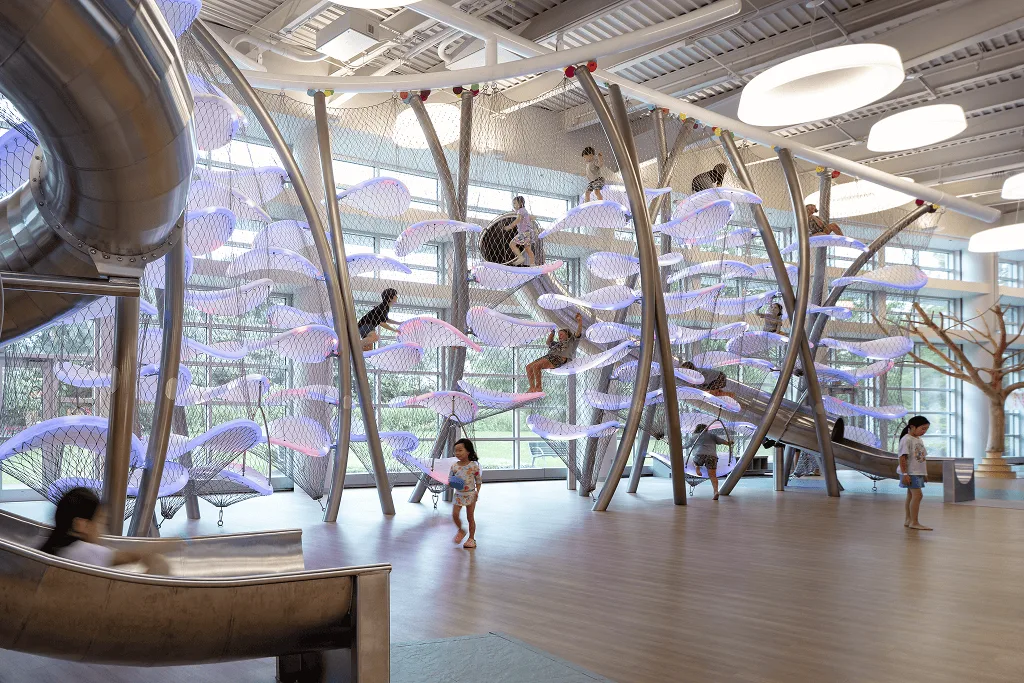 Children climbing at several heights through blue and lilac platforms, the steel slide entrance on the left