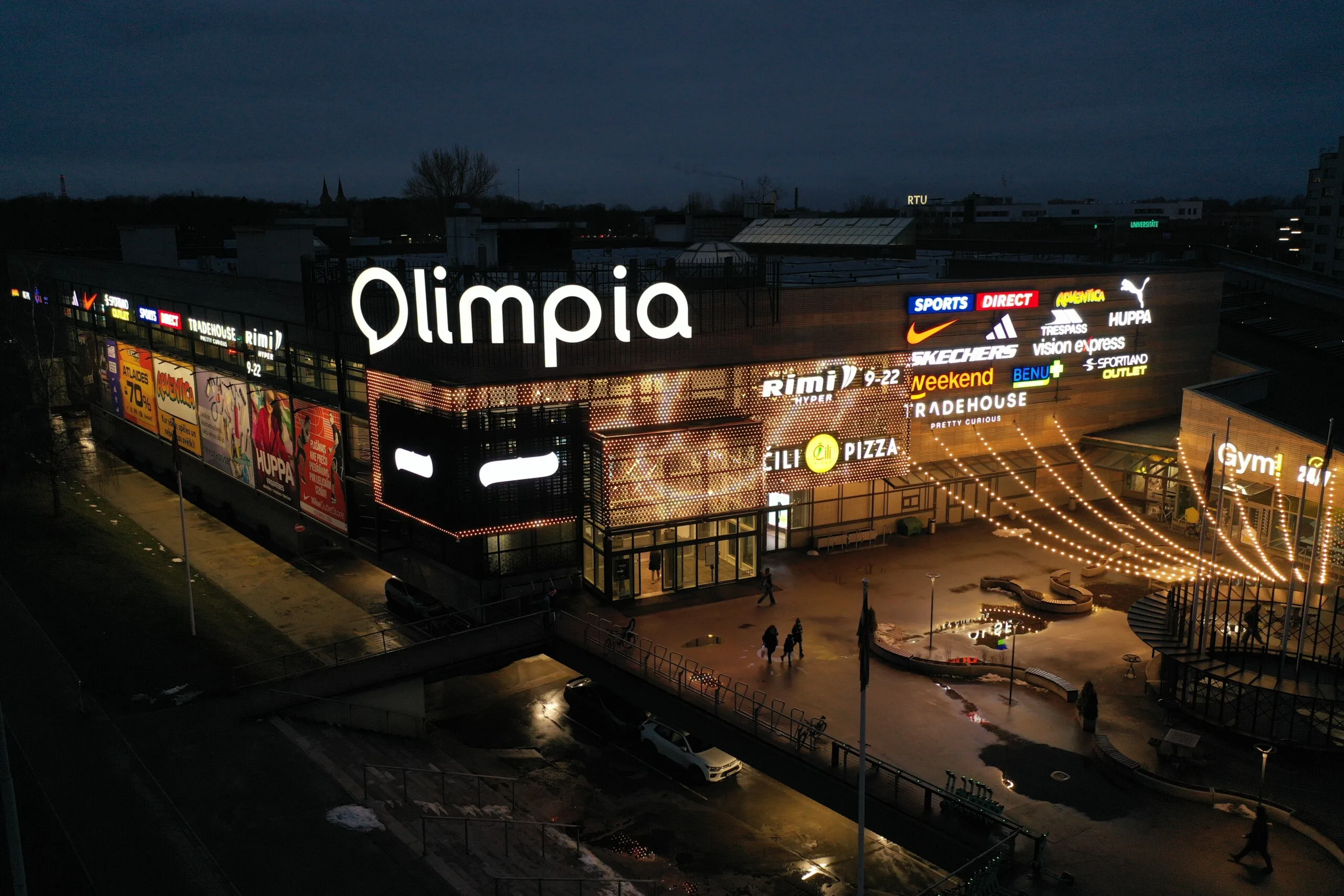 The facade nearly blacked out with a single white shape on the panel, warm light spilling from the shopfronts