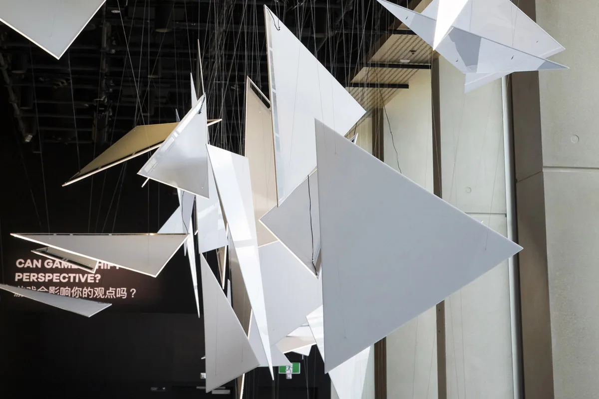 Angular white panels close up, the lit wall text asking whether gaming can shift your perspective behind them