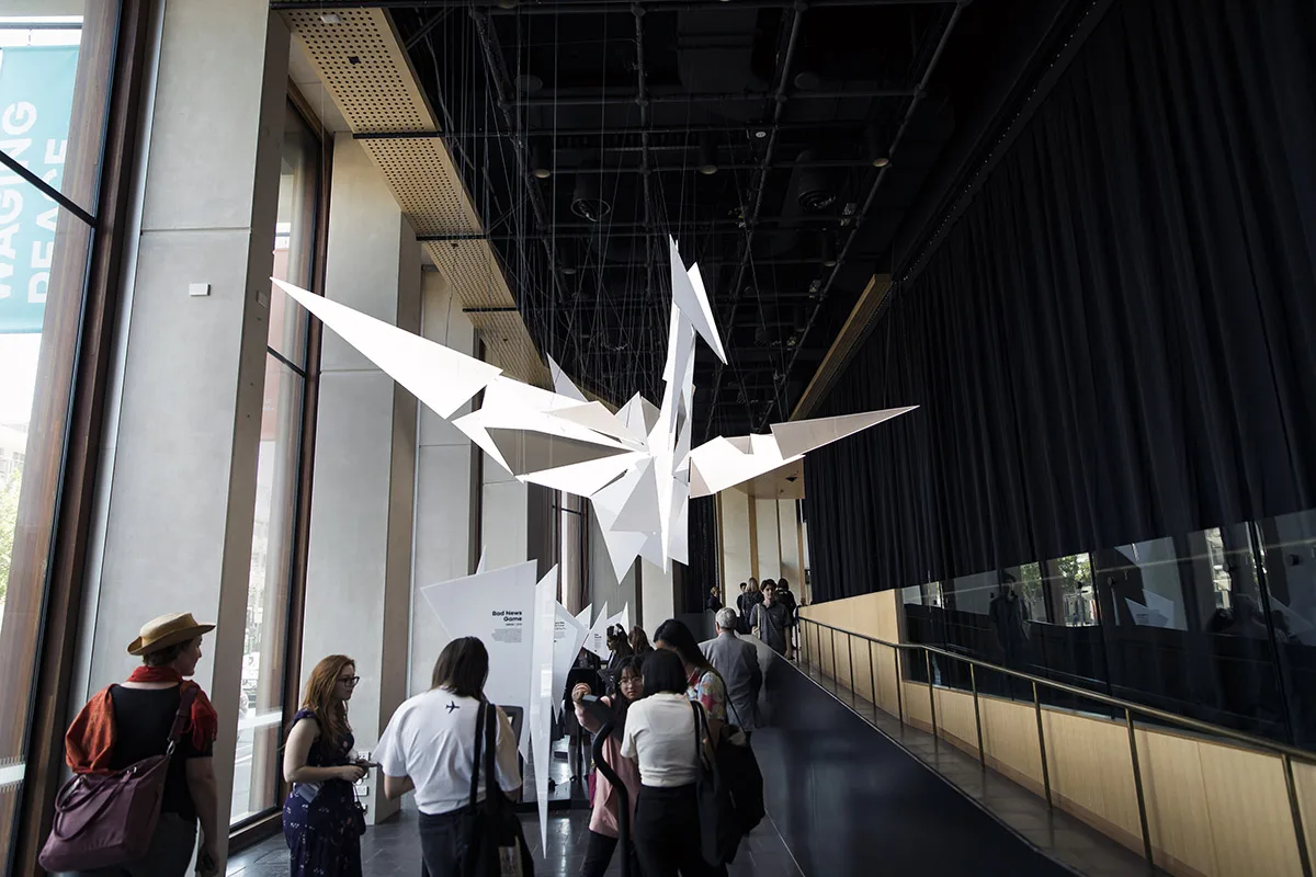 From the far end of the walkway the triangles resolve into the crane, visitors gathered underneath looking up