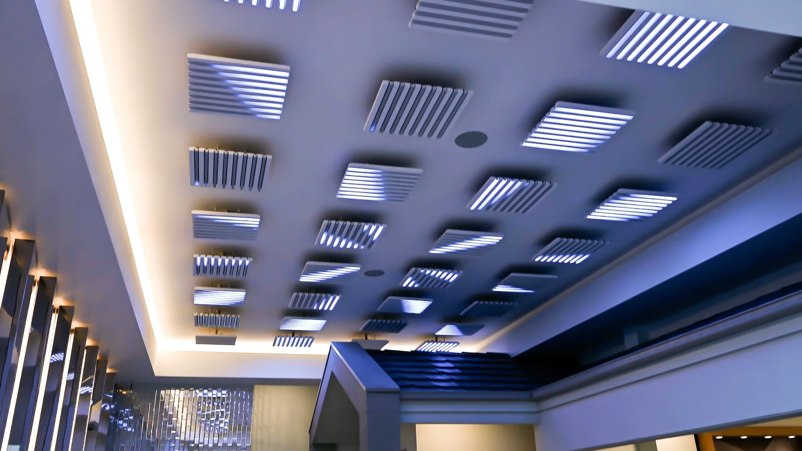The ceiling seen from below, pods lit blue and white with cove lighting tracing the perimeter of the bulkhead