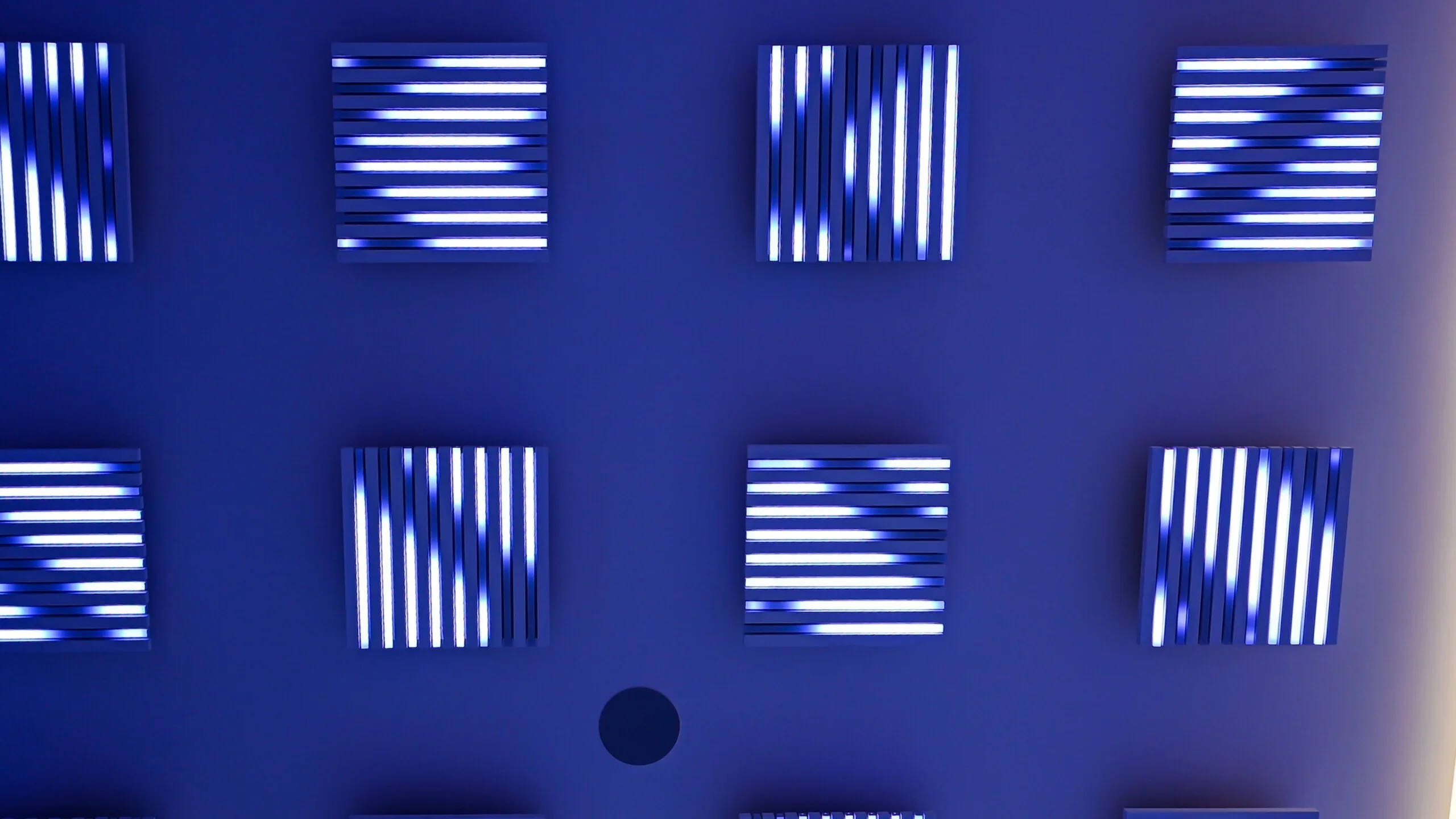 Close view of the pods on a deep blue ceiling, each square holding stripes of bright white light