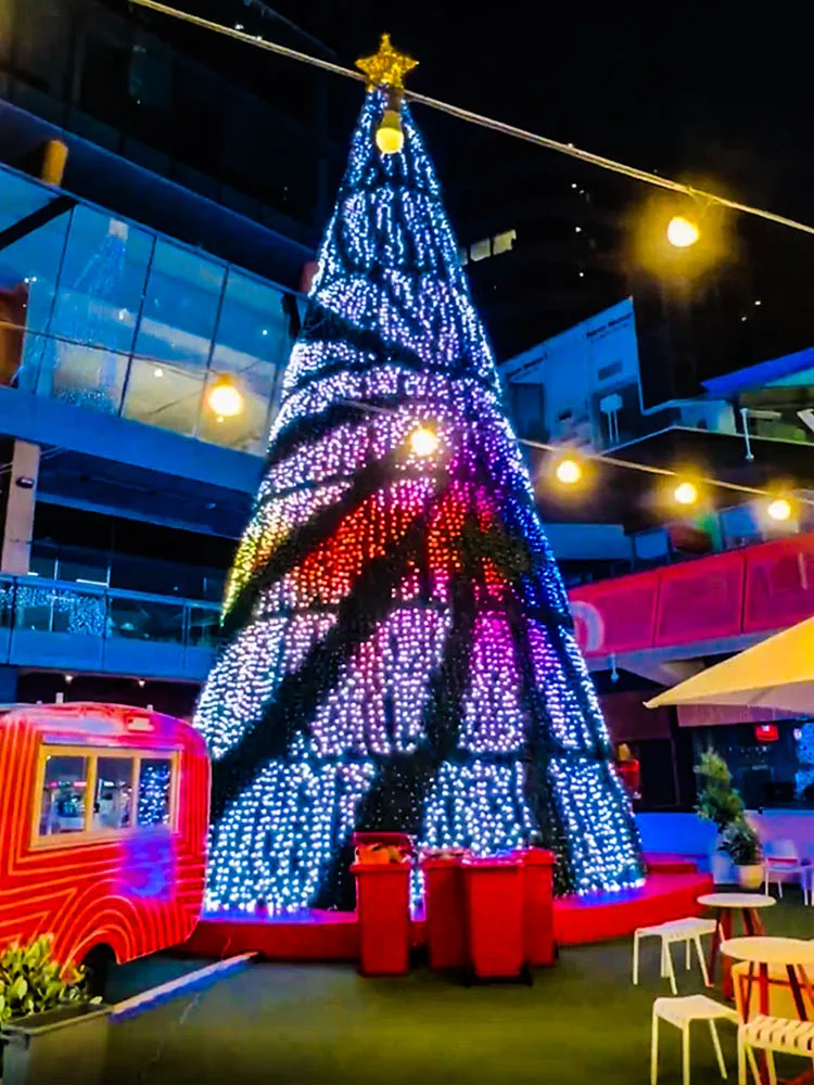 The cone in blue and magenta with a bright chase spiralling around it, a red bus and stacked gift boxes at its foot