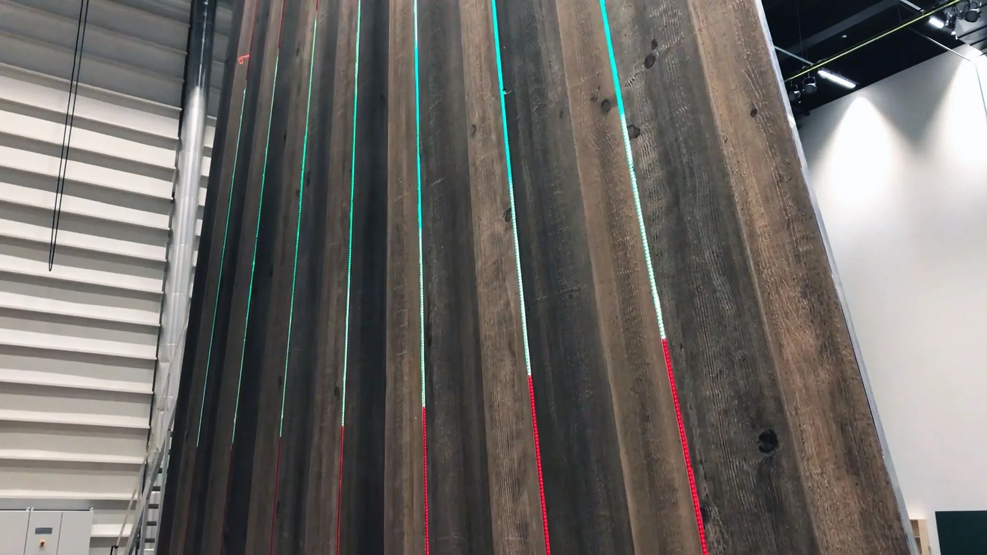 Looking along the raked timber set panels with thin pixel strips picked out in white, green, teal and red