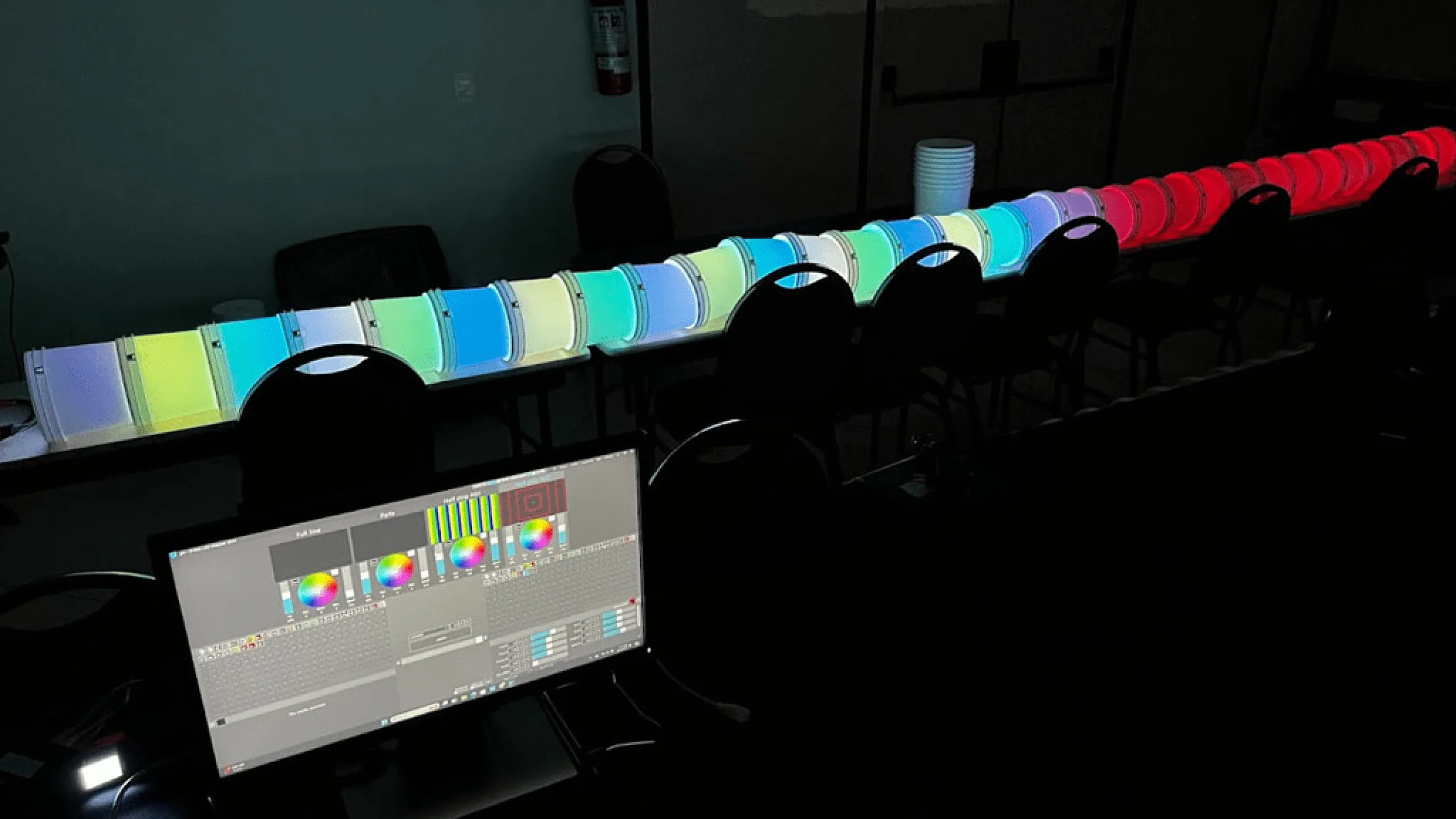 A straight test run of the bucket tube lit in pastel rainbow in a dark room, a laptop running ELM on the bench beside it