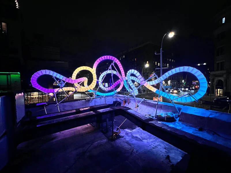 Loops lit purple, blue and orange along a raised walkway at night, an empty pool washed blue in the foreground