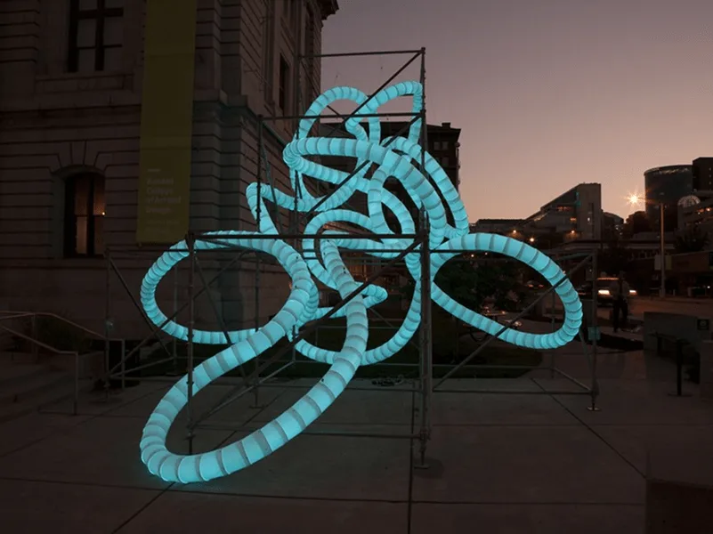 The scaffold piece at dusk lit an even turquoise, sunset sky and the lit windows of the stone building behind
