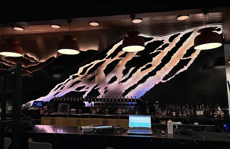 The SnowGlow installation lit above the bar, its carved slopes washed in colour