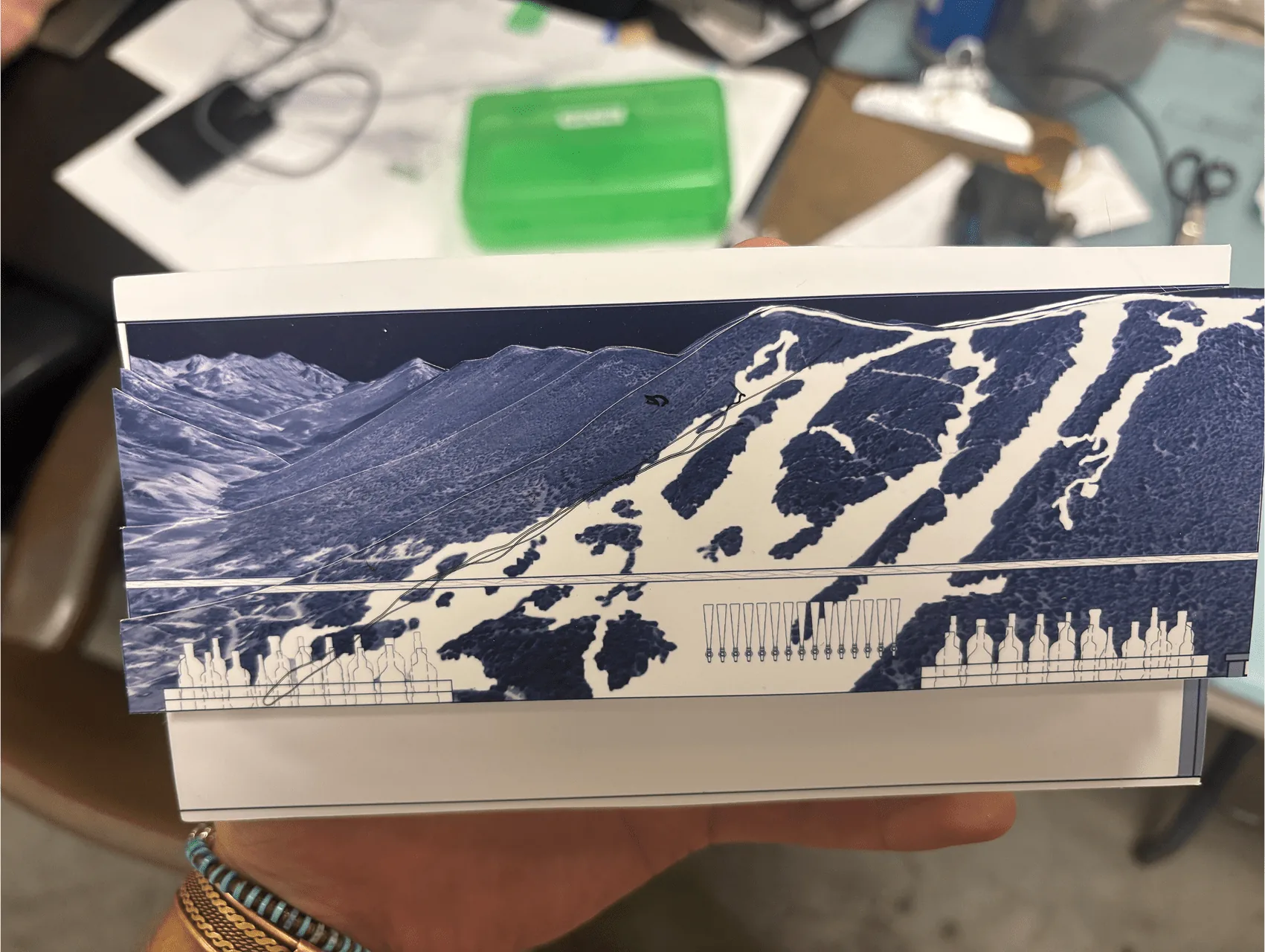 A hand holding the layered concept model of the carved ski-slope panels