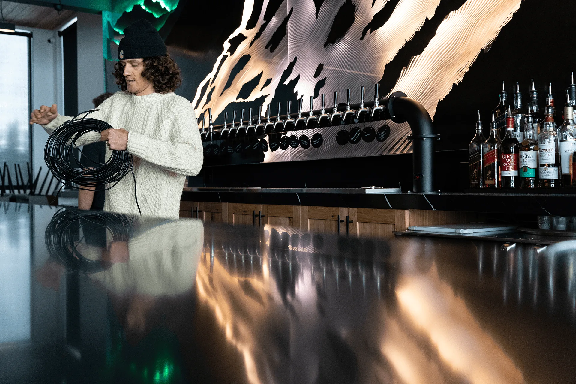 A coil of cable being carried along the bar while the sculpture is lit overhead