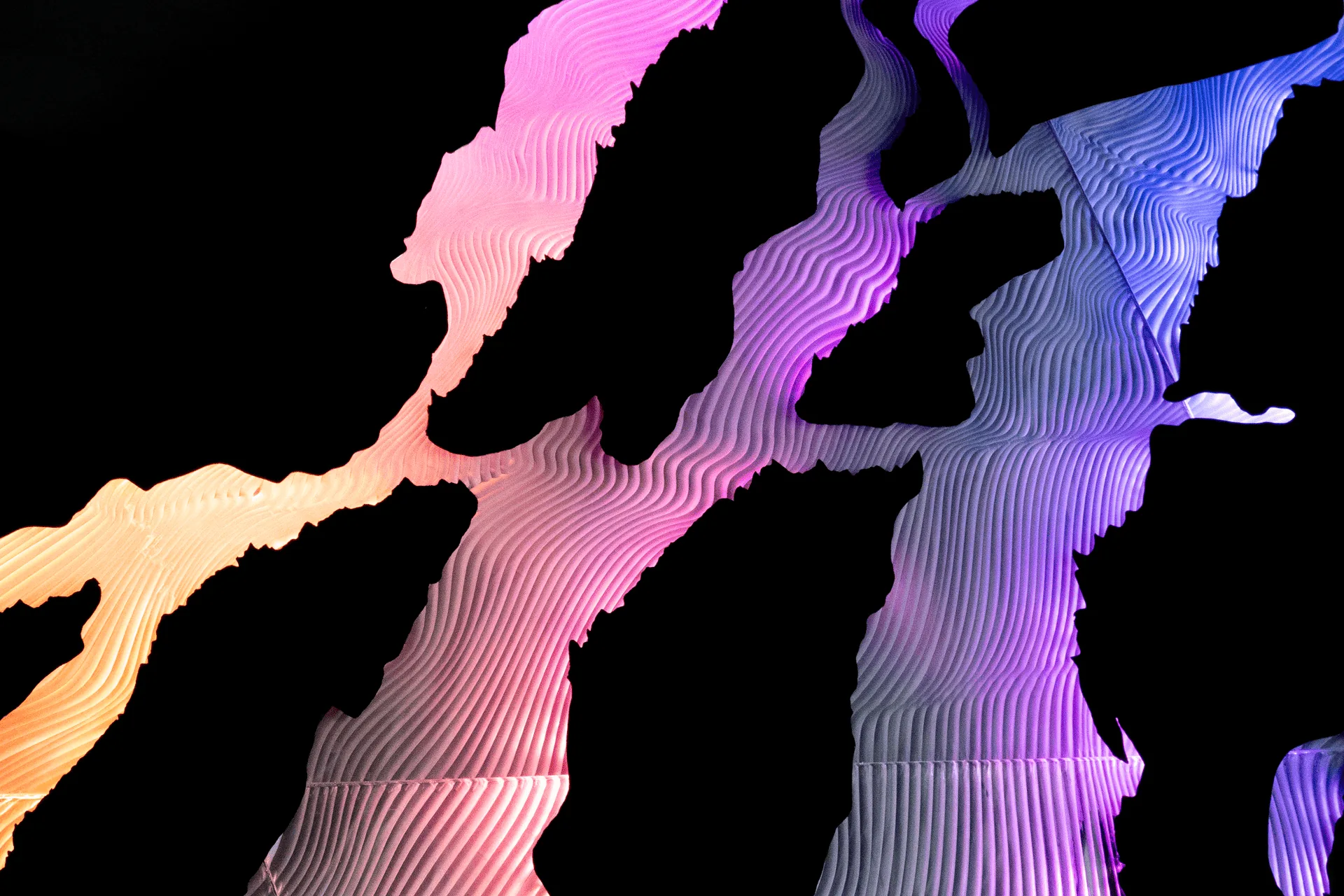 Close view of the layered acrylic slopes edge-lit in pink, violet and amber