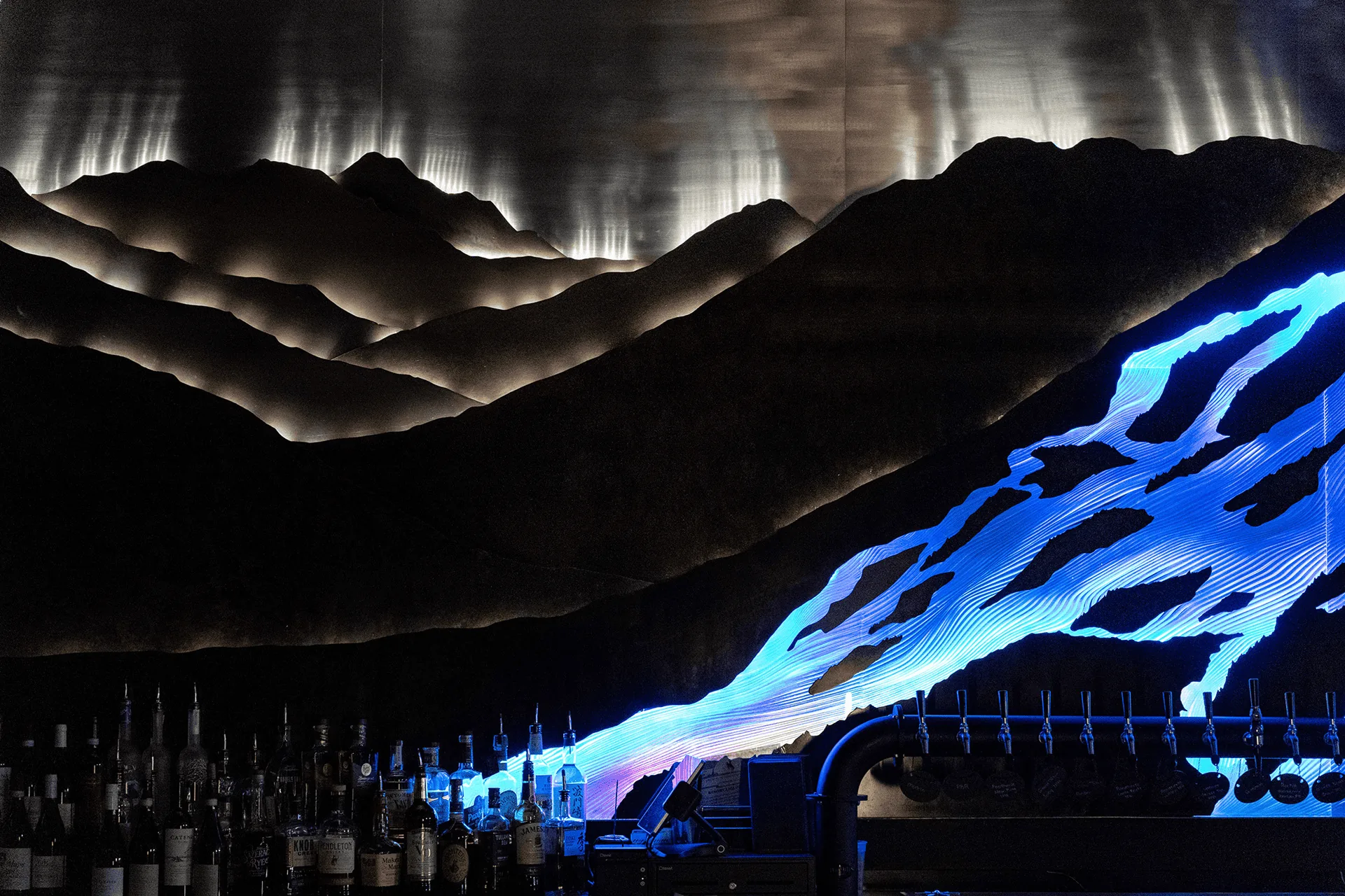 Wide view of the full artwork over the bar, warm peaks above cool blue slopes