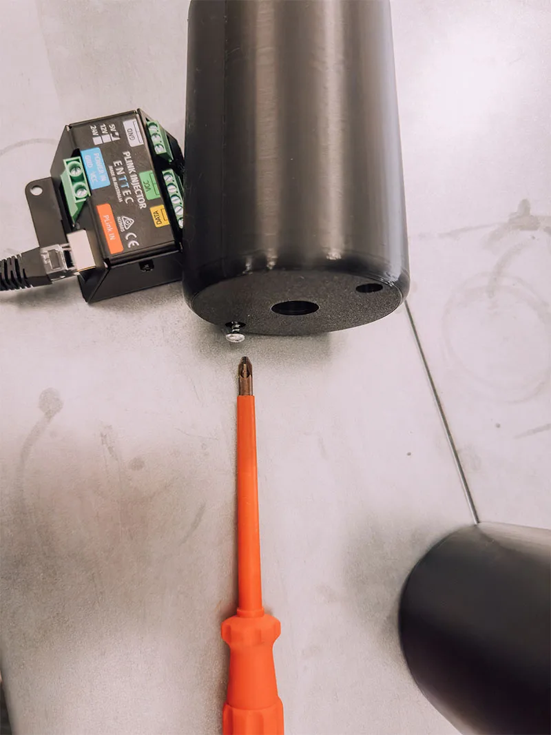 A canopy stood upright on the bench with its injector wired at the base, an orange screwdriver resting beside it