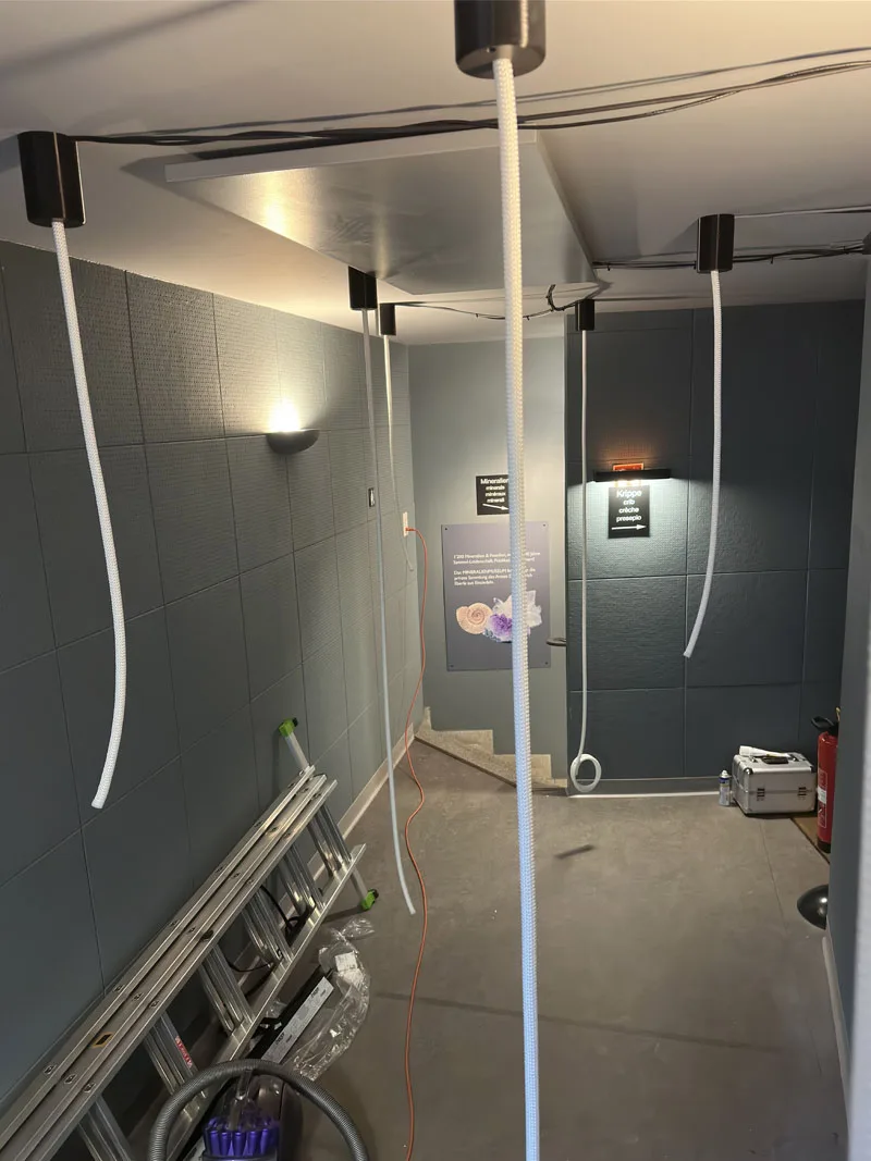 The same gallery from the other end, a single rope dropped from a black ceiling canopy ready to be dressed
