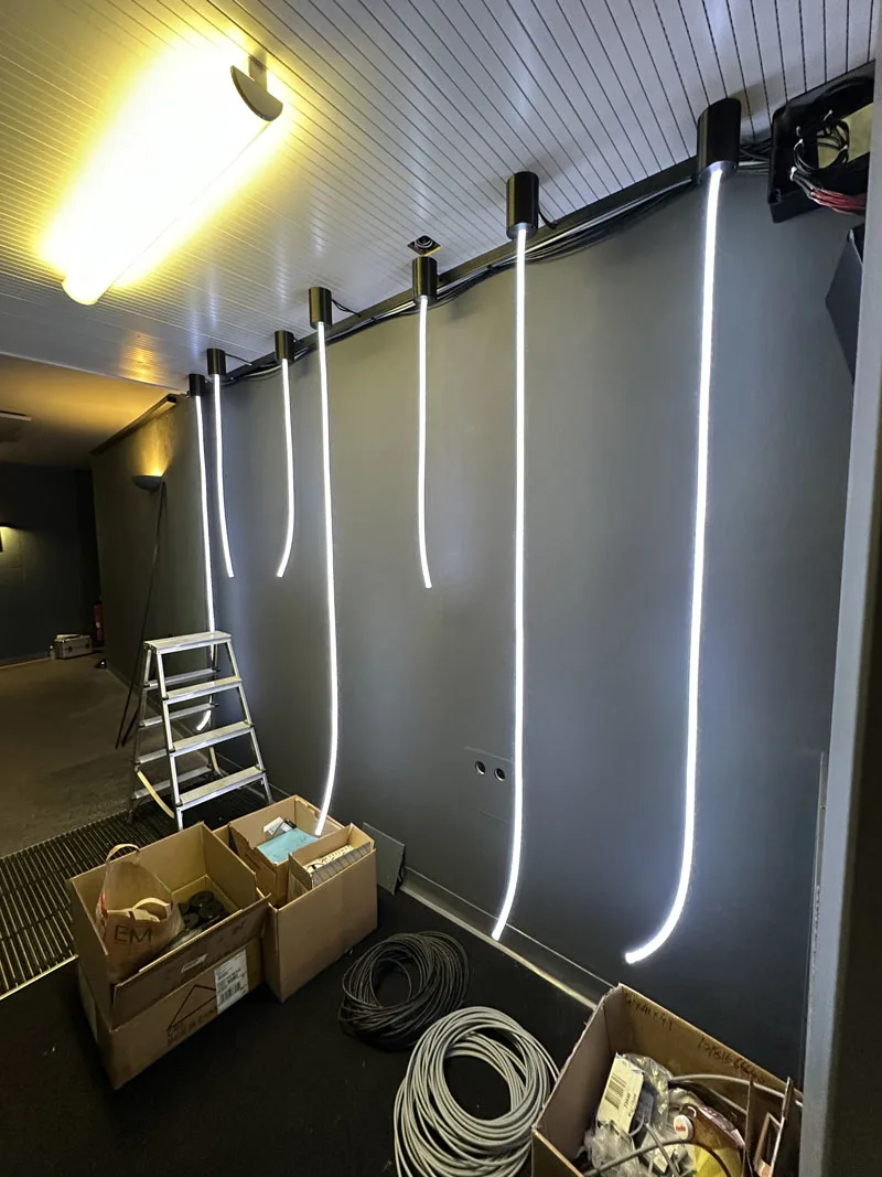 A row of ropes lit white along the corridor wall, packing boxes and a cable reel still on the floor