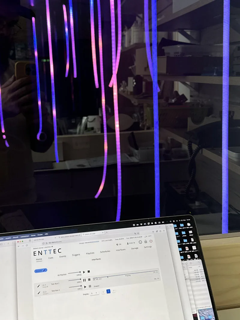 Pink and violet ropes reflected in a dark screen, with a laptop open on an ENTTEC configuration page below