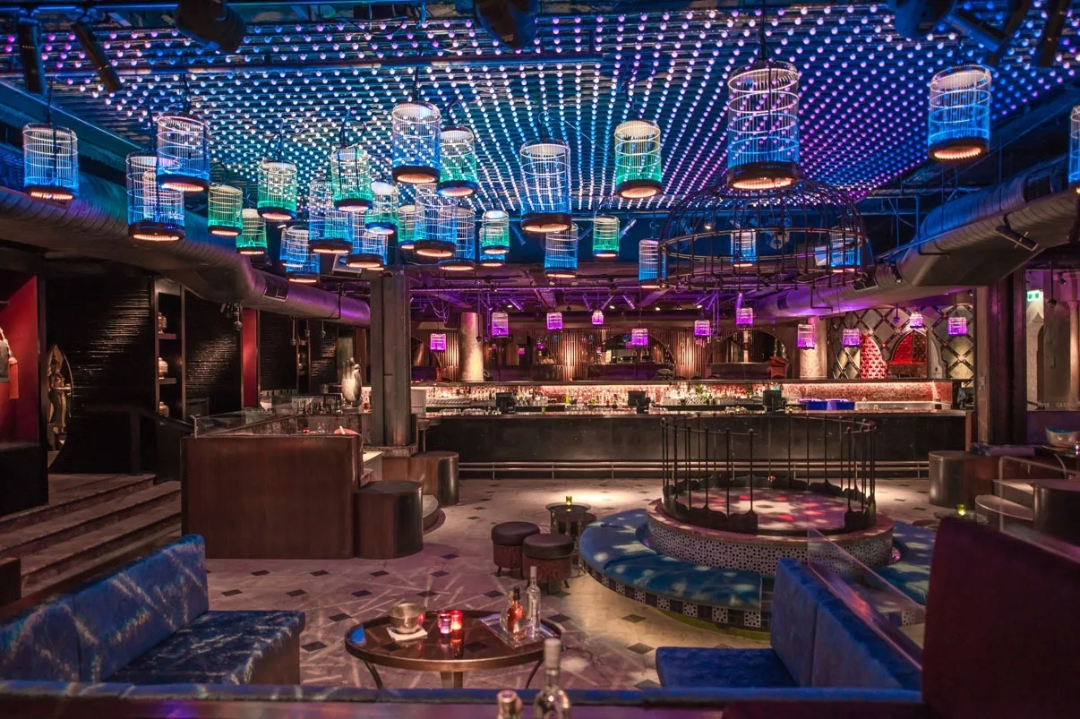 The bar and seating booths lit blue and violet, the pixel dot ceiling running a rippling pattern overhead