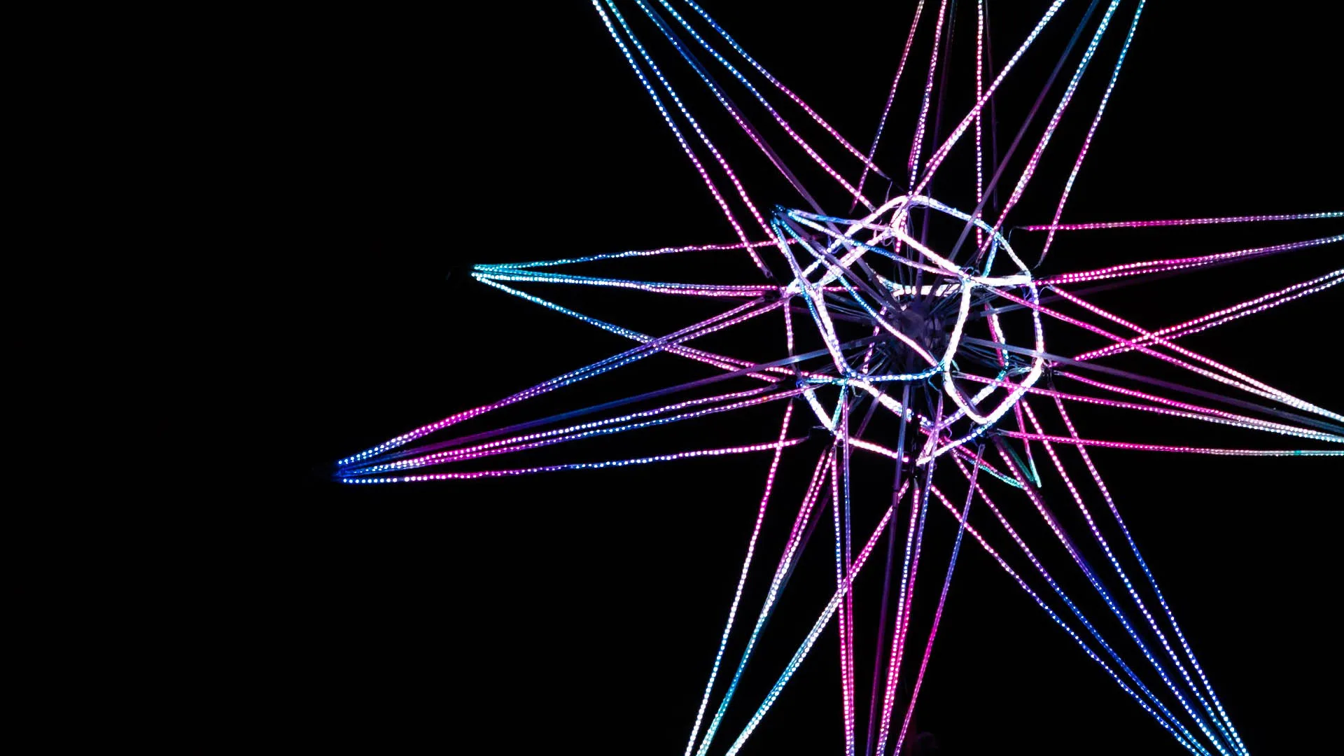 Tighter still on the core, the spokes cropped at the frame edge so the wire sphere and the pixel dots along each tube read clearly