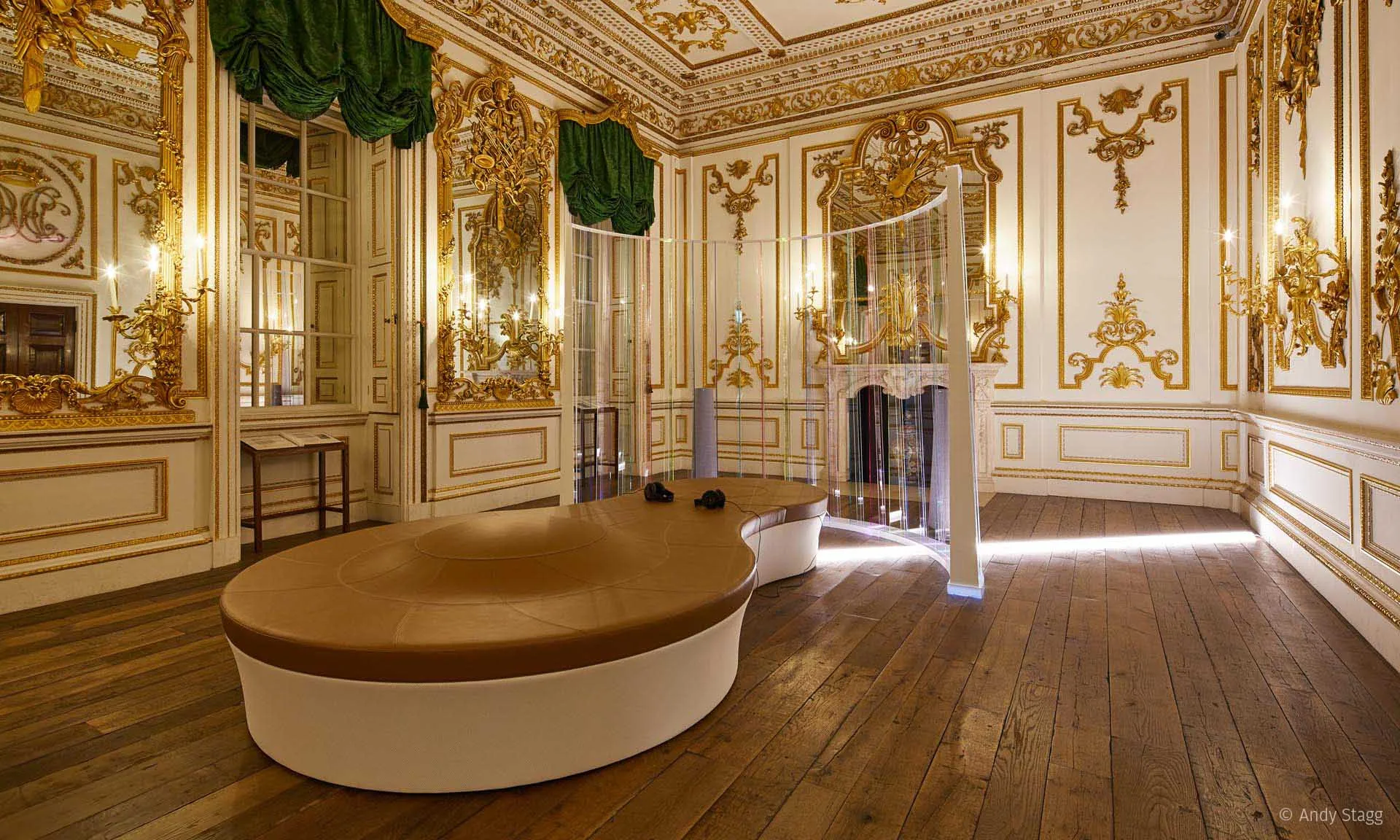 The Norfolk House Music Room lengthwise, a curved tan bench in the centre and the lit screen wrapped around its far end