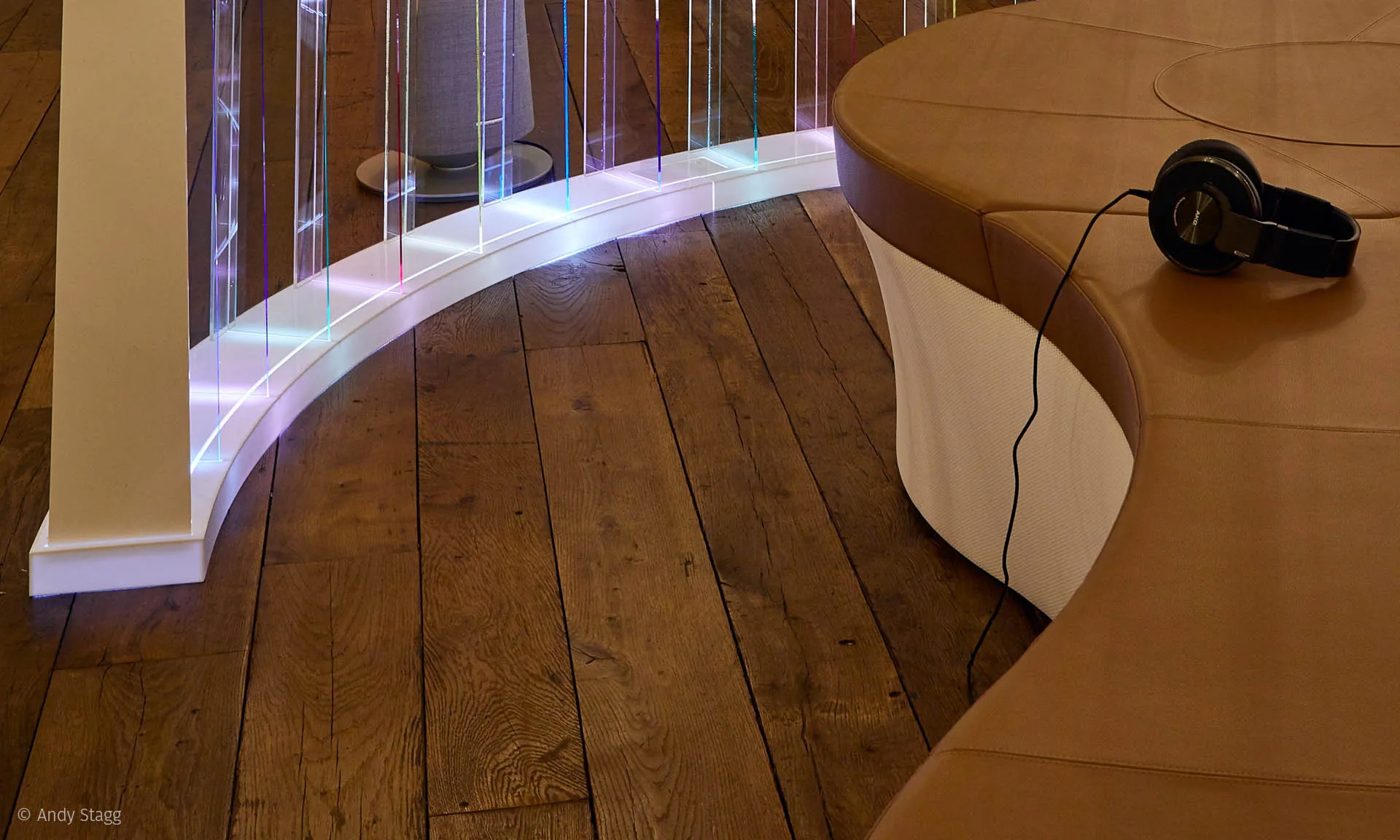 The curved lit base following the edge of the bench, a pair of headphones and their cable resting on top