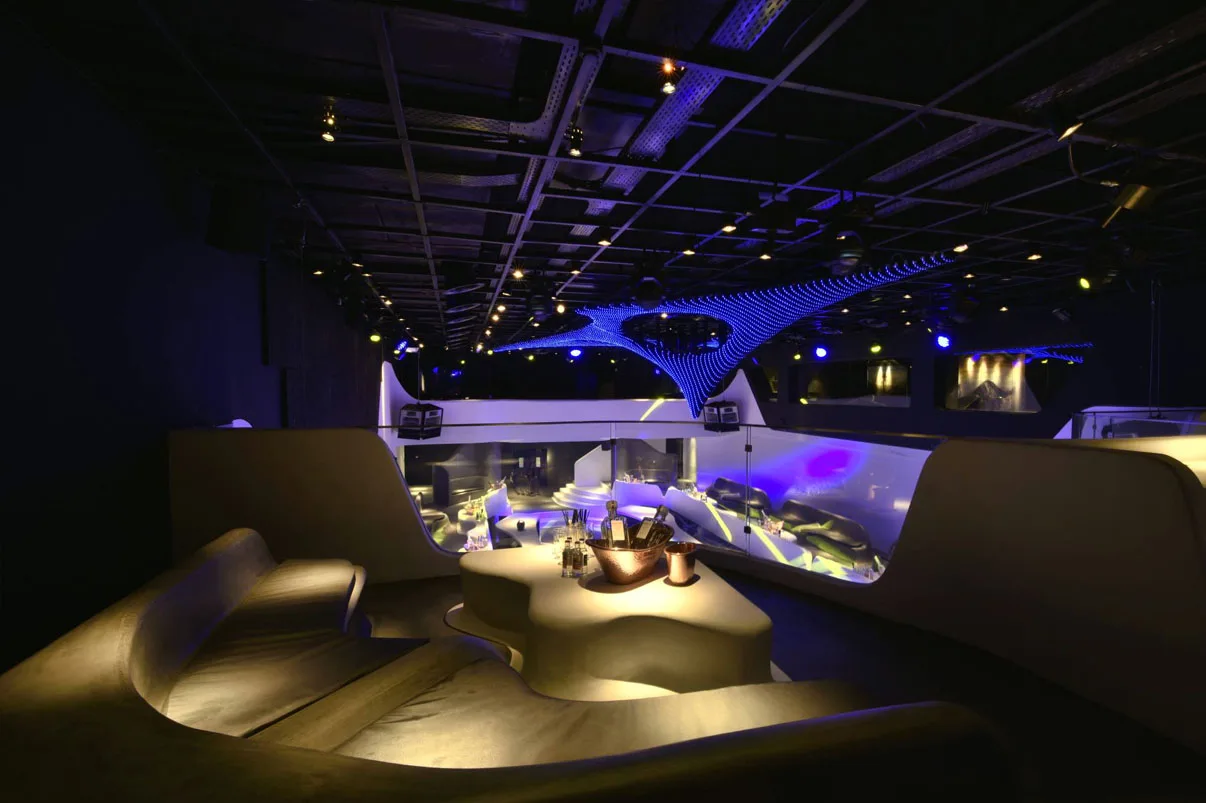 The venue empty with house lights up, the sculpture glowing blue above white moulded seating and the sunken bar